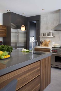 a modern kitchen with stainless steel appliances and wood cabinets, along with fruit on the counter