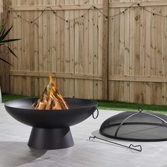 a fire pit sitting on top of a patio next to a fence