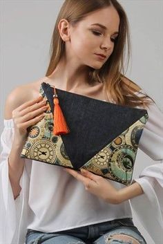 a woman holding a purse with an orange tassel