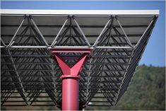 a pink pole under a metal structure with trees in the background