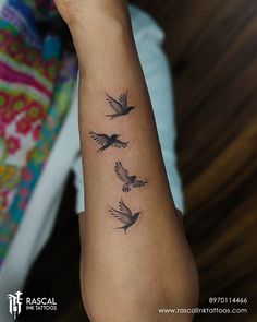 a woman's arm with three small birds on the left side of her arm