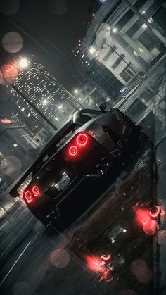 the back end of a black sports car on a city street at night with red lights