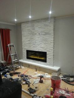 a living room with a fire place and tools on the floor