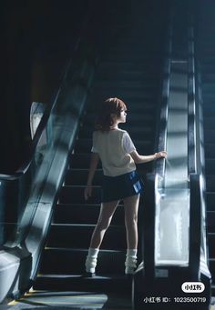 a woman standing on an escalator with her back to the camera and looking up