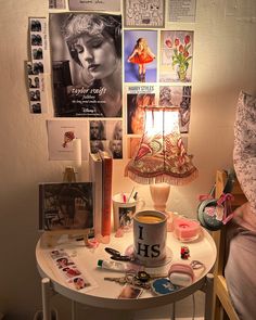 a table topped with lots of clutter next to a wall covered in posters and pictures