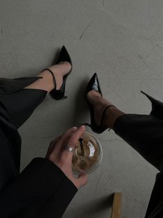 a woman in high heels is holding a wine glass with her feet on the floor