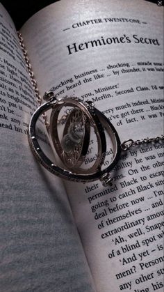 an open book with a silver necklace on it