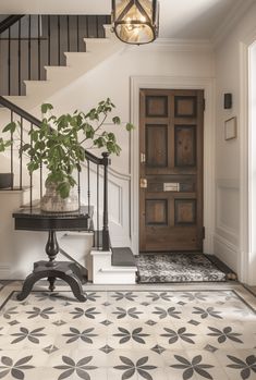 an entryway with stairs and a potted plant on the table next to it