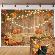 a man holding a pumpkin in front of a wooden wall with fall leaves on it