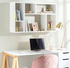 a laptop computer sitting on top of a desk next to a white book shelf filled with books