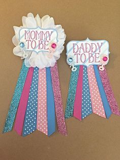 two ribbons with the words mommy to be and daddy to be on them hanging from a wall