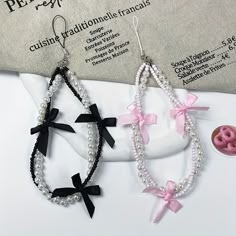 two pairs of earrings with pink bows and white pearls are on top of a table