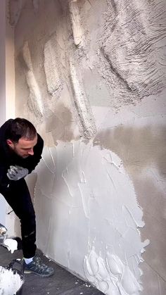 a man is painting the wall with white paint on it and his feet are in the air