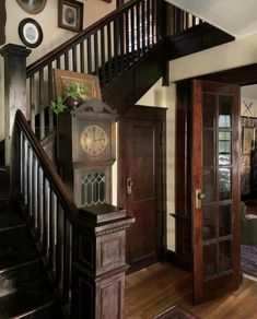 a clock sitting on top of a wooden floor next to a stair case in a house