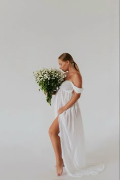 a woman in a white dress holding flowers