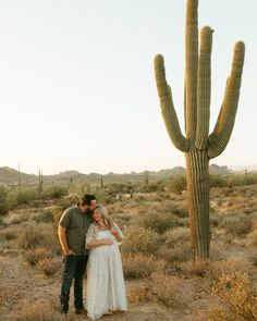 a man and woman standing in front of a cactus