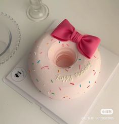 a white frosted donut with a pink bow on top