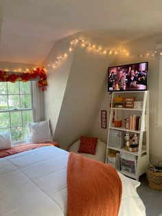 a bedroom with a bed, window and television on the wall next to it's bookshelf