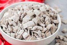 a white bowl filled with dog food on top of a red cloth next to a pile of cookies