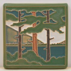 a ceramic tile with trees and mountains in the background