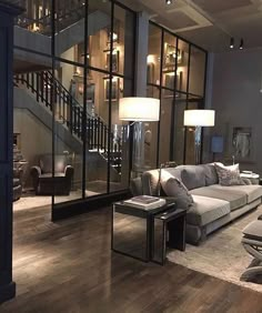 a living room filled with lots of furniture and large glass windows next to a stair case