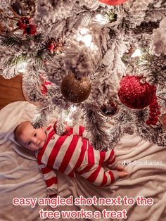 a baby laying in front of a christmas tree with the caption easy angel shot next to the tree works a treat