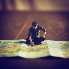 a man sitting on the ground looking at a map