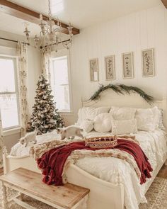 a white bed sitting in a bedroom next to a christmas tree on top of a wooden table