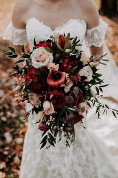 a woman in a wedding dress holding a bridal bouquet with red and white flowers