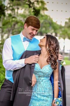 a man and woman in formal wear standing next to each other with their arms around each other