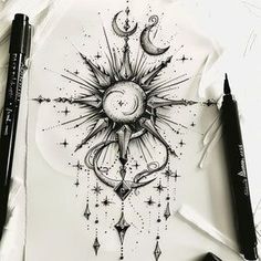 a drawing of a sun and moon with stars on the paper next to some pens