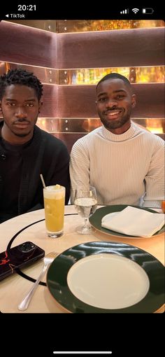 two men sitting at a table with plates and drinks