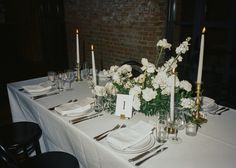 the table is set with white flowers and silverware