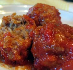 two meatballs covered in sauce on a white plate