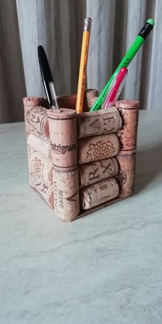 there are several pens and pencils in the cork holder on the counter top,