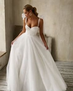 a woman in a white wedding dress leaning against a wall