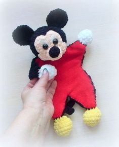 a hand holding a small stuffed animal in the shape of mickey mouse