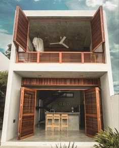 an open air house with wooden shutters on the front and second story balcony area