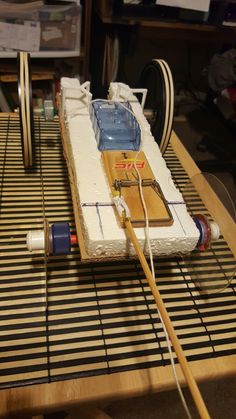 a model boat is sitting on top of a table with two paddles in front of it