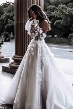 a woman in a white wedding dress standing next to an old pillar with columns behind her