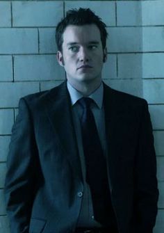 a man in a suit and tie leaning against a wall