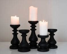 black candles are lined up on a white table