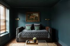 a living room filled with furniture and a painting on the wall over a coffee table