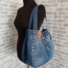 a woman's handbag hanging on a mannequin head with a brick wall behind it