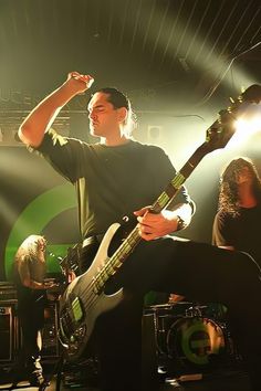 a man holding his arm up in the air as he plays an electric guitar on stage