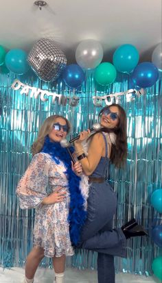 two women standing next to each other in front of balloons