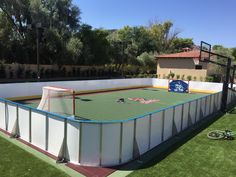 an above ground hockey rink is in the middle of a backyard with grass and artificial turf