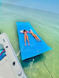 a woman laying on a blue mat in the water