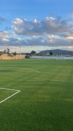 an empty soccer field with the sky in the background