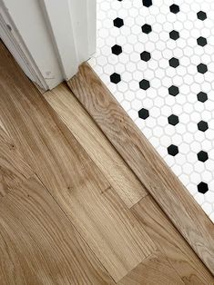 an open door on the floor in front of a white tile wall with black hexagonal tiles